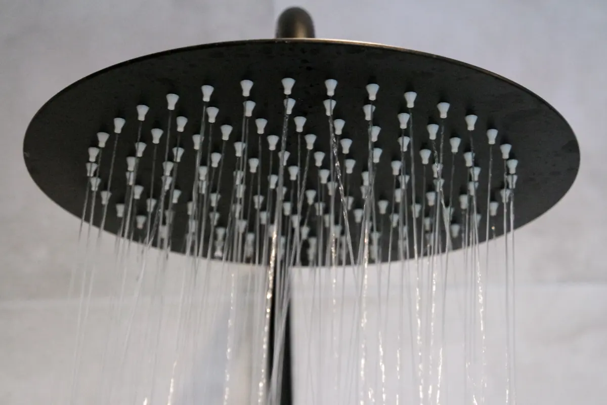 Round black rainfall shower head with water streaming down